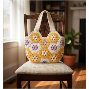 Può includere: Borsa tote all'uncinetto fatta a mano con un design floreale. La borsa presenta un motivo a nido d'ape con motivi floreali gialli, bianchi e viola. La borsa è su una sedia di legno con un sedile a fantasia floreale.