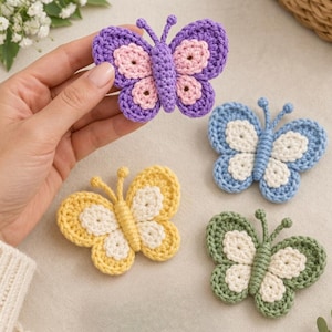 May include: Four crocheted butterfly appliques in purple and pink, blue and white, yellow and cream, and green and cream. Each butterfly features a central body, two antennae, and four wings with a solid outer border and a contrasting inner color.