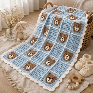 Può includere: Una coperta per neonati all'uncinetto color azzurro e bianco con un motivo a griglia ripetuto e applicazioni di facce d'orso marroni in ogni quadrato. La coperta presenta un bordo bianco all'uncinetto smerlato ed è appoggiata su un cesto di vimini.
