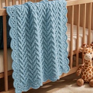 May include: A light blue, crocheted baby blanket with a chevron pattern and scalloped edges. The blanket is draped over the side of a wooden crib. A stuffed giraffe toy sits next to the crib.