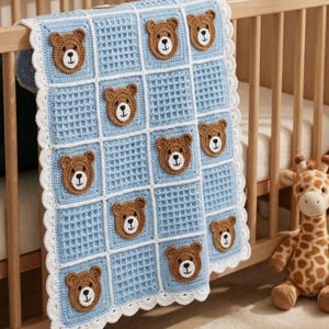 May include: A light blue and white crocheted baby blanket with a repeating pattern of brown teddy bear faces. The blanket is draped over a wooden crib, with a stuffed giraffe toy visible in the background.