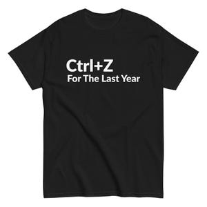 Peut inclure: T-shirt noir avec l'inscription blanche "Ctrl+Z For The Last Year" centrée sur la poitrine. Le t-shirt a des manches courtes et un col rond. Le tissu semble être un mélange de coton doux.