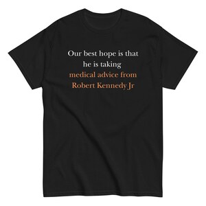 Peut inclure: T-shirt noir avec texte blanc et orange. Le texte se lit comme suit : « Notre meilleur espoir est qu'il suive les conseils médicaux de Robert Kennedy Jr. »