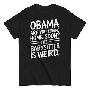 Op de afbeelding: Zwart t-shirt met witte tekst. De tekst luidt: "OBAMA ARE YOU COMING HOME SOON? THE BABYSITTER IS WEIRD." Het lettertype is vet en licht verweerd.