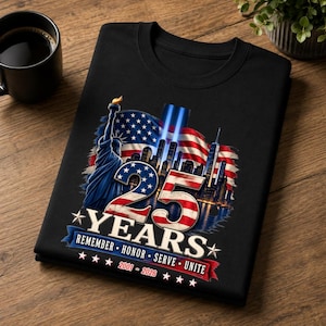 Peut inclure: Un sweat-shirt noir à col rond arborant un motif de la Statue de la Liberté, du drapeau américain et de la ligne d'horizon de New York. Le design inclut le texte 25 YEARS, REMEMBER HONOR SERVE UNITE et les années 2001-2026 en blanc et rouge.