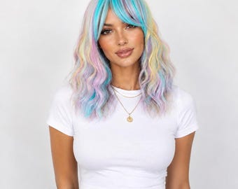 Puede incluir: Una peluca de longitud media con cabello ondulado en una paleta de colores pastel con reflejos azules, rosas, amarillos y lavanda. El cabello está peinado con flequillo que enmarca el rostro, combinado con una camiseta blanca lisa.