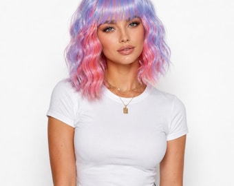 May include: A shoulder-length wig featuring wavy hair in a blend of pastel purple and vibrant pink tones with straight bangs. The hair is styled with a center part and loose waves that frame the face, creating a multi-colored appearance.