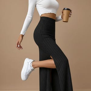 Può includere: Un completo da donna con un top corto bianco a maniche lunghe e una gonna nera a coste con spacco laterale. L'outfit è abbinato a scarpe da ginnastica bianche. Una tazza di caffè di carta marrone è tenuta in mano.
