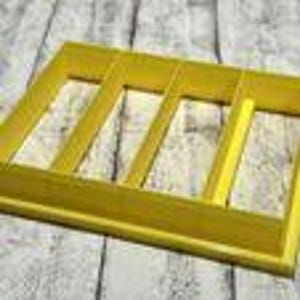May include: A yellow wooden tray with four rectangular compartments for organizing utensils or other small items.