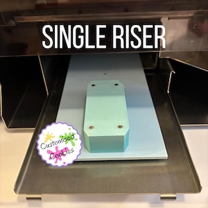 May include: A light teal single riser with four metal fasteners is displayed on a light blue surface. The words "SINGLE RISER" are printed in white above the riser. A colourful logo that says "Customised Cookies" is in the lower left corner.
