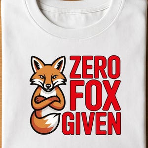 以下が含まれることがあります： 白いTシャツ。オレンジ、茶色、白の漫画のキツネが腕を組んでいる。赤い文字で「ZERO FOX GIVEN」と書かれている。Tシャツは折りたたまれている。