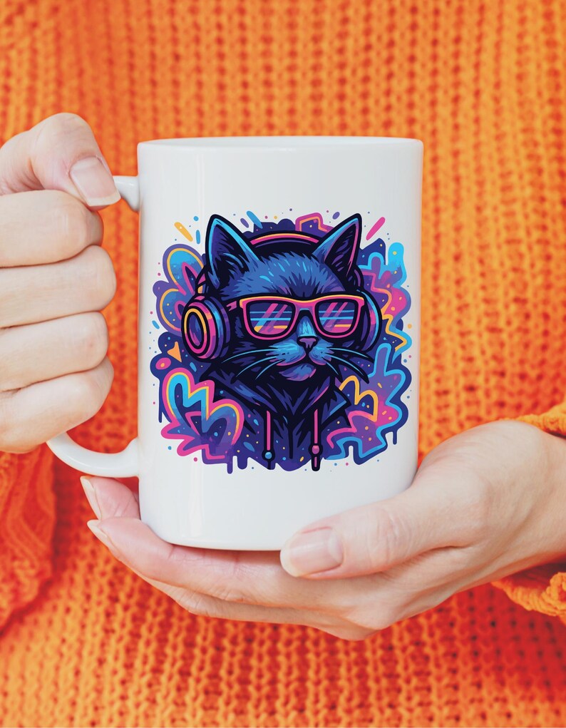 May include: White ceramic mug featuring a black cat wearing headphones and neon pink glasses. The cat is set against a colorful, graffiti-style background. The mug is held by a person wearing an orange sweater.