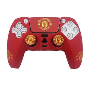 May include: Red PlayStation 5 controller featuring the Manchester United emblem. The controller has the team's crest on the touchpad and buttons. The controller has silver buttons and a black center.
