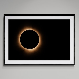 Può includere: Una fotografia di un'eclissi solare totale, che mostra la corona del sole come un anello luminoso attorno alla sagoma scura della luna.