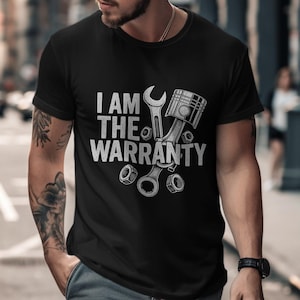May include: Black t-shirt with the text "I AM THE WARRANTY" in white, accompanied by illustrations of a wrench, piston, and nuts. The design has a distressed, vintage look, suitable for mechanics or automotive enthusiasts.