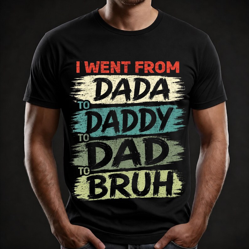May include: Black t-shirt with the text "I WENT FROM DADA TO DADDY TO DAD TO BRUH" in a distressed, brushstroke style. The text is in red, cream, teal, and green colors.