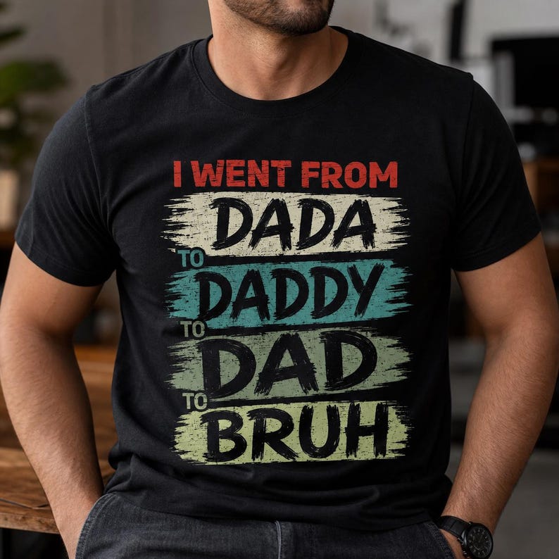 May include: Black t-shirt with the text "I WENT FROM DADA TO DADDY TO DAD TO BRUH" in red, white, teal, and yellow-green. The text is layered on top of each other with a brush stroke effect.