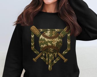 Könnte beinhalten: Schwarzes Sweatshirt mit Baseball-Design. Der Baseball ist eine Mischung aus Grün, Braun und Beige, mit zwei gekreuzten Schlägern. Das Design hat ein strukturiertes, gestricktes Aussehen und einen tropfenden Effekt.