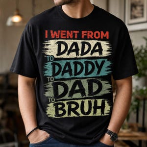May include: Black t-shirt with the text "I went from Dada to Daddy to Dad to Bruh" in a distressed, multi-colored design. The text is layered on horizontal stripes of red, cream, teal, and green.