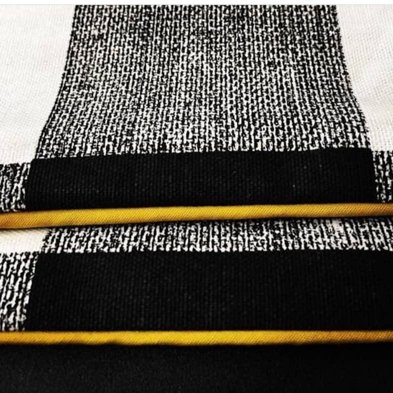 May include: Close up of black and white checkered fabric with a yellow trim. The fabric has a textured, woven look.