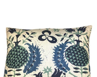 May include: Decorative pillow with a botanical design. The pillow features a cream-colored background with a repeating pattern of blue and green floral elements, including stylized pomegranates and leaves. The design is symmetrical and creates a visually appealing aesthetic.