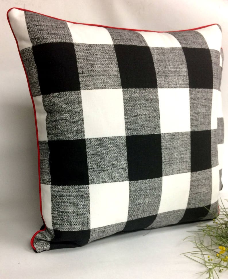 May include: Black and white buffalo plaid throw pillow with red piping.