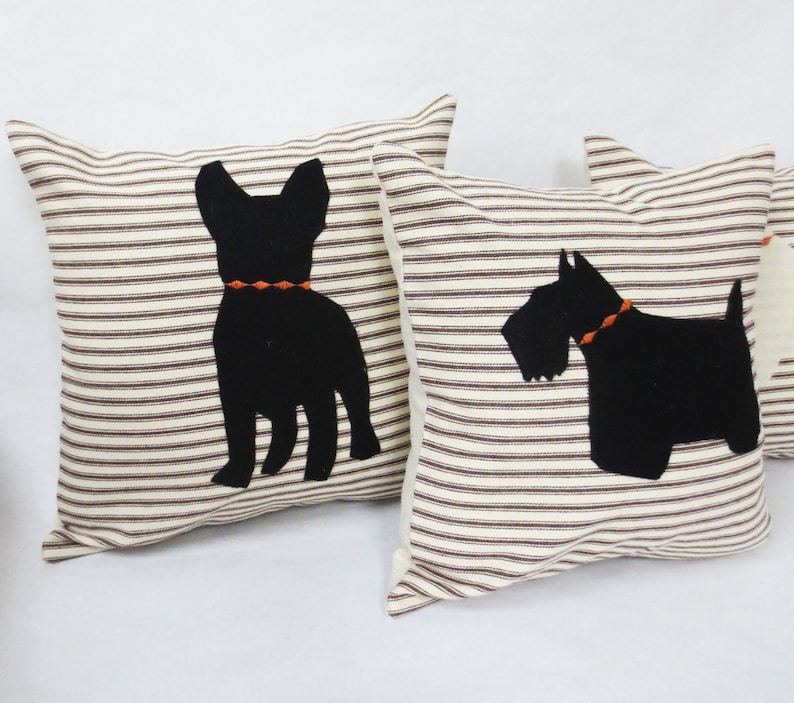 May include: Two decorative throw pillows with black silhouette images of dogs. The pillows have a white background with brown stripes. One pillow features a French Bulldog and the other a Scottish Terrier.