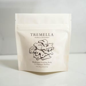 Op de afbeelding: Een witte zak met een zwart-witte illustratie van een paddenstoel. De zak is gelabeld "Tremella Tremella fuciformis Mushroom Fruiting Body 1:1 Extract Powder 2 oz (57 g) / 30 servings"