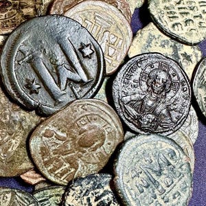 Peut inclure: Une collection de pièces de monnaie antiques avec divers motifs et inscriptions. Les pièces sont principalement de couleur bronze et argent, avec des signes d'usure visibles. Certaines pièces présentent des figures religieuses, d'autres des symboles et du texte.