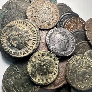 Puede incluir: Una colección de monedas romanas antiguas, con diversos diseños e inscripciones. Las monedas son principalmente de bronce y cobre, con desgaste visible. Algunas monedas muestran perfiles de emperadores y otras figuras históricas.
