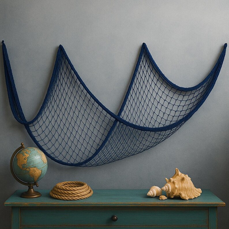 Puede incluir: Una red de pesca decorativa azul marino cuelga de una pared gris sobre un mueble de madera color turquesa. Un globo terr&aacute;queo, una cuerda enrollada y conchas marinas se exhiben en el mueble, creando un tema n&aacute;utico.