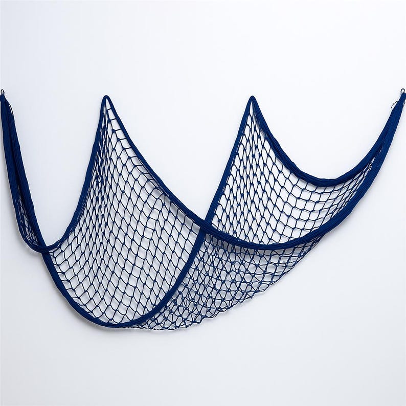 Puede incluir: Una red de pesca decorativa azul marino, suspendida sobre un fondo blanco. La red est&aacute; hecha de cuerda tejida, con un patr&oacute;n de malla en forma de diamante. Dise&ntilde;ada para colgar como decoraci&oacute;n de pared.