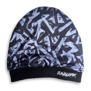 May include: A black beanie with a light blue graffiti-style pattern. The hat has a black ribbed cuff with a "JUNGLEFOX" patch. This winter hat is a stylish accessory.