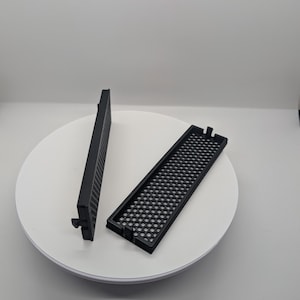 May include: Two black plastic vent covers with a honeycomb pattern. The covers are rectangular and have a slight curve to them.