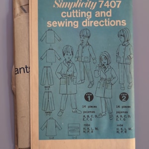 May include: A Simplicity 7407 sewing pattern instruction sheet with a light blue background. The document displays illustrations of children wearing pajamas and robes, labeled as view 1 and view 2, along with technical diagrams for garment construction.