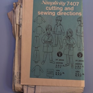 May include: A Simplicity 7407 sewing pattern envelope for size 1 pajamas and robes. The light blue front cover features black line drawings of children wearing the garments, with text detailing 14 pieces for views 1 and 2, plus cutting and sewing directions.