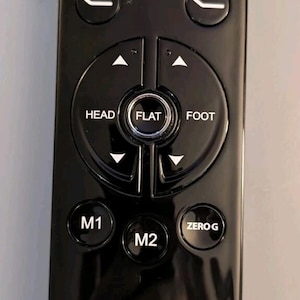 May include: A black Sleep Science remote control for an adjustable bed. The device features buttons labeled Massage, ZZZ, HEAD, FOOT, FLAT, M1, M2, and ZERO G, along with directional arrows and icons for bed positioning and comfort settings.