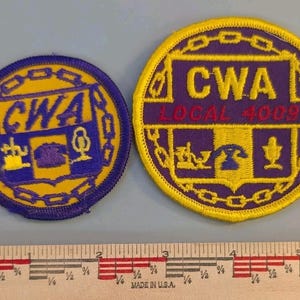 May include: Two circular embroidered patches featuring the text CWA and CWA LOCAL 4009 in yellow and red. The designs include icons of a telephone, a microphone, and a tool, surrounded by a chain border. A ruler shows the patches are 2 to 3 inches wide.