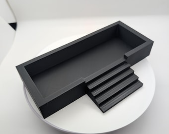 May include: A black plastic rectangular tray with a raised platform on one side. The platform has four steps leading up to the tray.