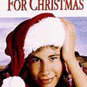 May include: A movie cover for Disney's I'll Be Home For Christmas starring Jonathan Taylor Thomas. The image features a person wearing a red and white Santa hat, with the film title and a short synopsis printed in black text against a light background.