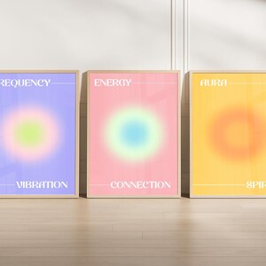 Puede incluir: Tres láminas enmarcadas con diseños de aura degradados. Las láminas presentan las palabras "Frecuencia", "Energía" y "Aura" en texto blanco. Cada lámina tiene una combinación de colores diferente: morado, rosa y amarillo, con un degradado circular central.