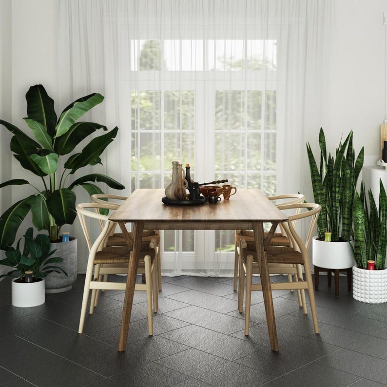 May include: A wooden dining table with four chairs, set in a modern dining room with large windows and potted plants. The table has a light wood finish and the chairs have a natural wood finish.