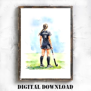 Puede incluir: Impresión en acuarela de una jugadora de hockey sobre hierba con uniforme negro con la palabra "CUSTOM" y el número 11 en la espalda. La jugadora sostiene un palo de hockey sobre un campo verde con un fondo de cielo azul. La imagen está enmarcada en un marco de madera marrón rústico.