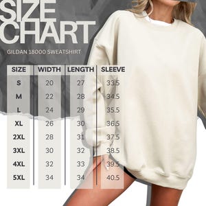 May include: A cream-colored crewneck sweatshirt shown with a size chart titled SIZE CHART GILDAN 18000 SWEATSHIRT. The chart lists sizes S through 5XL with corresponding width, length, and sleeve measurements in inches for each size category.