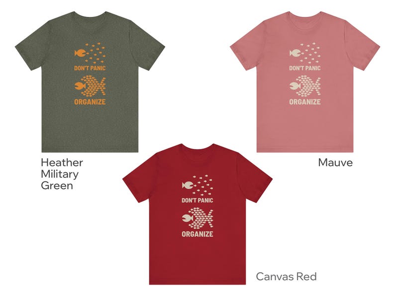 May include: Three t-shirts in heather military green, mauve, and canvas red. Each shirt features a graphic of two fish and the words "DON'T PANIC ORGANIZE" in orange or white. The shirts are short-sleeved.
