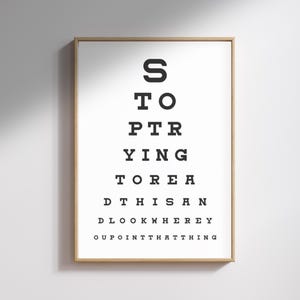 May include: Framed print with a white background and black text arranged in a classic eye chart format. The text reads "STOP TRYING TO READ THIS AND LOOK WHERE YOU POINT THAT THING."