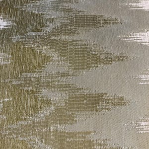 May include: Close-up of a textured fabric with a pattern of horizontal brushstrokes. The fabric features a blend of olive green, beige, and white hues, creating a subtle, abstract design. The weave is visible, adding depth.