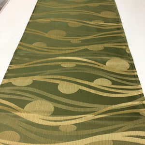 May include: Green table runner with a wavy pattern and gold circles. The circles have a textured surface.