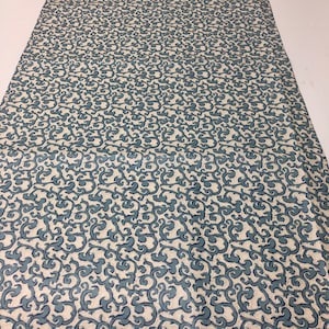 May include: White fabric with a blue swirling pattern. The pattern is a repeating design of stylized swirls.