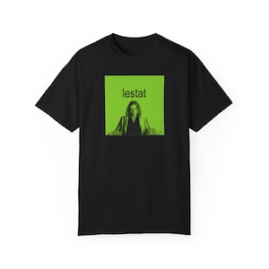 May include: Black t-shirt with a green square graphic featuring a photo of a person and the text "lestat" in white.